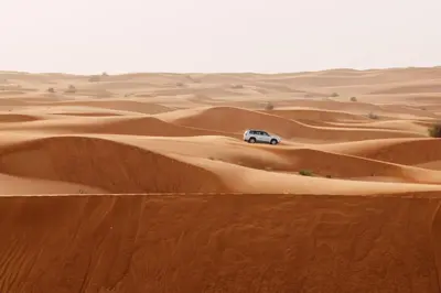 a car driving through the desert at Merzouga desert Luxury Camp in Merzouga