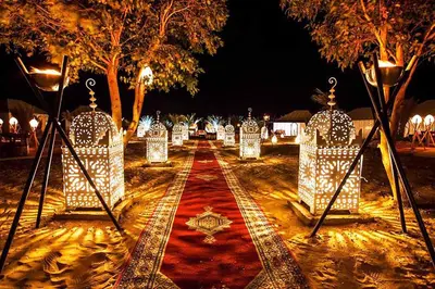 a walkway with lights in a park at night at Merzouga desert Luxury Camp in Merzouga