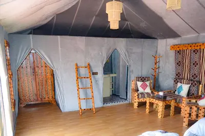 a room with a tent with a chair and a ladder at Merzouga desert Luxury Camp in Merzouga