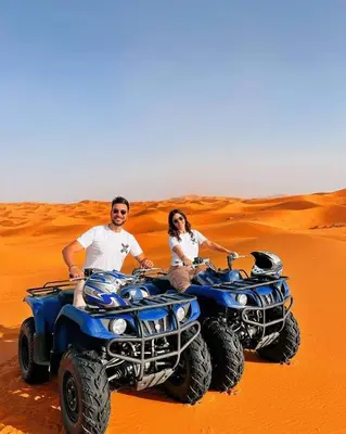 a man and woman sitting on atvs in the desert at Merzouga desert Luxury Camp in Merzouga