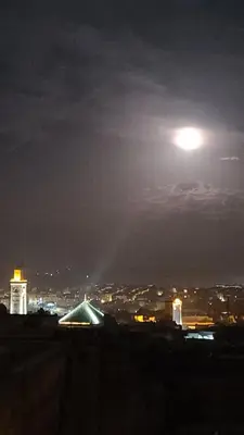 a view of a city at night with the moon at RIAD DAR DIWAN in Fès