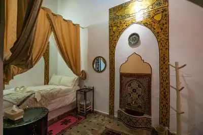 a small room with a bed and a cross on the wall at RIAD DAR DIWAN in Fès