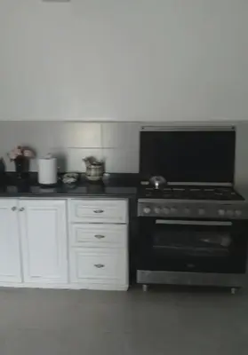 a kitchen with a black stove and white cabinets at Amazing house separate of Villa with Swimming Pool in Marrakech