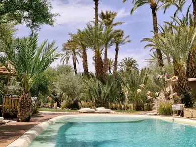 a swimming pool in a yard with palm trees at L'Ma Lodge in Skoura