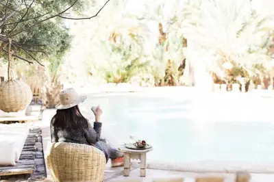 a woman sitting on a chair by a pool at L'Ma Lodge in Skoura