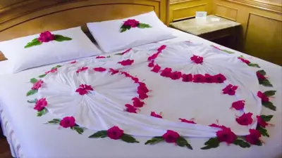 a white bed with pink flowers on it at شقق للكراء اليومي بالرشيدية Errachidia in Er Rachidia