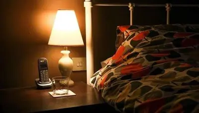 a lamp and a cell phone on a table next to a bed at شقق للكراء اليومي بالرشيدية Errachidia in Er Rachidia