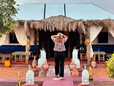 a woman standing on a stage with her hands on her head at Merzouga Nomad Camp in Merzouga