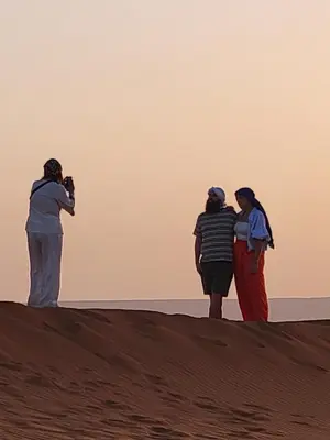 three people standing on top of a sand dune at Merzouga Nomad Camp in Merzouga