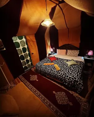 a small room with a bed in a tent at Merzouga Nomad Camp in Merzouga