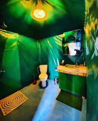 a green bathroom with a toilet and a sink at Merzouga Nomad Camp in Merzouga