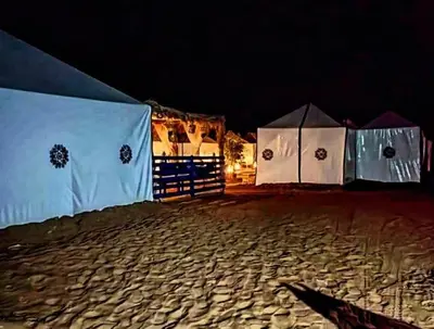 a row of tents on a beach at night at Rachid Luxury Camp in Merzouga