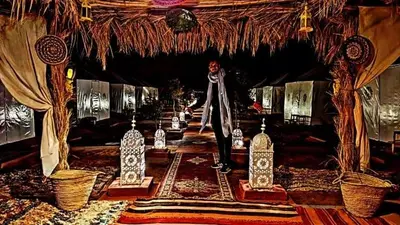 a man is standing in a room with bottles at Rachid Luxury Camp in Merzouga