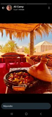 a person holding a tray of food on a table at Rachid Luxury Camp in Merzouga