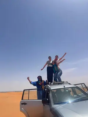 a group of people standing on the roof of a car at Rachid Luxury Camp in Merzouga