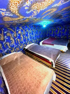 two beds in a room with a blue wall at Merry Desert Camp in Merzouga