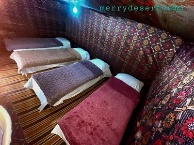 a group of four beds with blankets and pillows at Merry Desert Camp in Merzouga