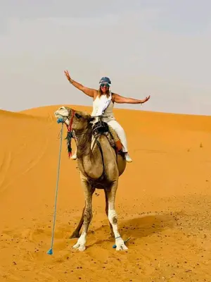 a woman riding a camel in the desert at Merry Desert Camp in Merzouga