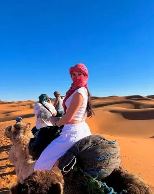 three people riding on the camel in the desert at Merry Desert Camp in Merzouga