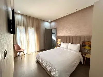 a bedroom with a white bed and a chair at Villa Naouma in Marrakech