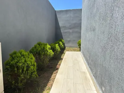 a wooden walkway leading into a gray wall with bushes at Villa Naouma in Marrakech