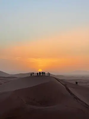 a group of people walking in the desert at sunset at Desert Bliss Luxury Camp in Merzouga