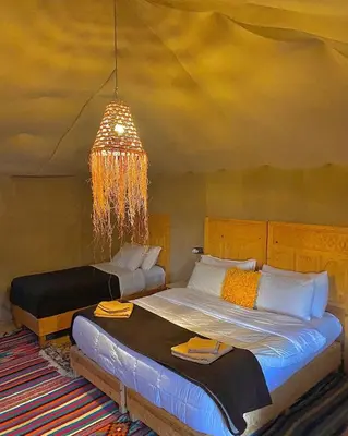 a bedroom with two beds and a chandelier at Desert Bliss Luxury Camp in Merzouga