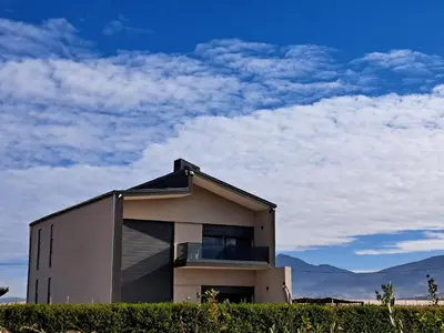 a house on top of a hill with mountains in the background at Villa Deluxe Au Pied de l'Atlas Béni Mellal in Ksar et Tlatia