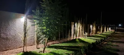 a row of trees next to a wall at night at Villa Deluxe Au Pied de l'Atlas Béni Mellal in Ksar et Tlatia