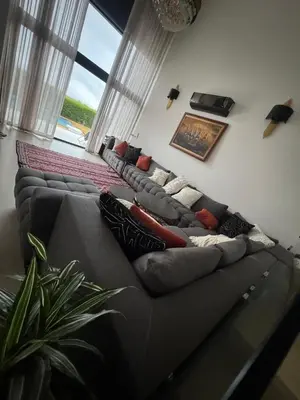 a living room with a gray couch with pillows at Villa Deluxe Au Pied de l'Atlas Béni Mellal in Ksar et Tlatia