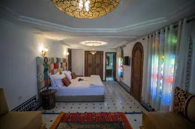 a bedroom with a white bed and a chandelier at DARIF's Riad & Spa in Fès