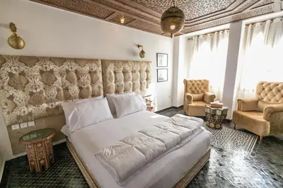 a bedroom with a large bed and two chairs at DARIF's Riad & Spa in Fès