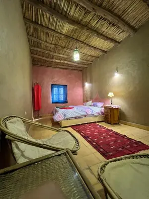 a room with two beds and a table and a ceiling at DAR MIRA DUNES Hassilabiad-Merzouga in Hassilabied