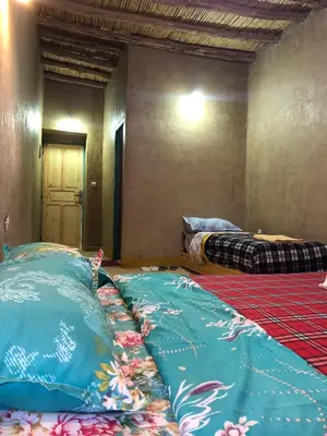 an empty room with two beds in a room at DAR MIRA DUNES Hassilabiad-Merzouga in Hassilabied