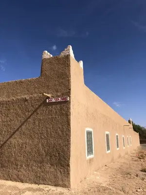 a brown building with a sign on the side of it at DAR MIRA DUNES Hassilabiad-Merzouga in Hassilabied