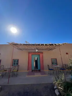 a building with tables and chairs in front of it at DAR MIRA DUNES Hassilabiad-Merzouga in Hassilabied