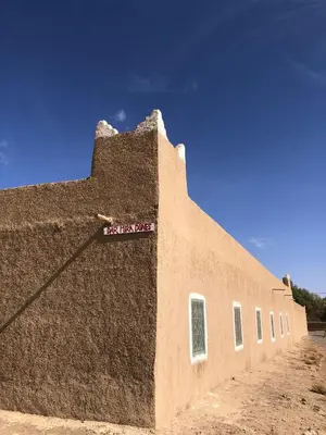 a brown building with a sign on the side of it at DAR MIRA DUNES Hassilabiad-Merzouga in Hassilabied