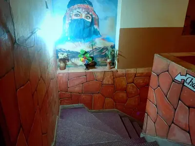 a bathroom with a painting of a person wearing a mask at Hotel Almanader in Boumalne