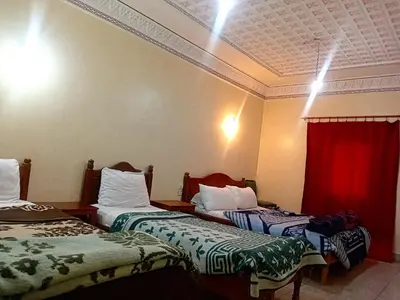 a hotel room with two beds and a red curtain at Hotel Almanader in Boumalne