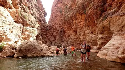 a group of people crossing a river in a canyon at Hotel Almanader in Boumalne