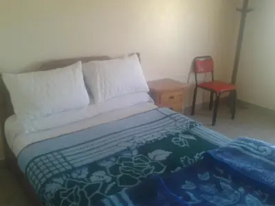 a bedroom with a bed with a red chair and a table at Hotel Almanader in Boumalne