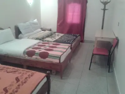 a room with two beds and a table and a chair at Hotel Almanader in Boumalne