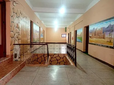 a hallway of a building with paintings on the walls at Hotel Almanader in Boumalne