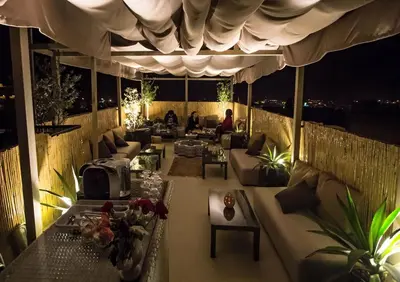 a room with couches and tables on a balcony at night at Riad Al Makan Fes & Spa in Fès