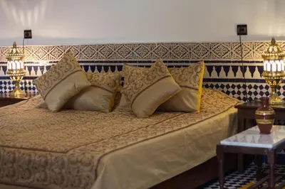 a bedroom with a large bed with gold pillows at Riad Al Makan Fes & Spa in Fès