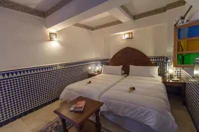 a hotel room with two beds and a table at Riad Al Makan Fes & Spa in Fès
