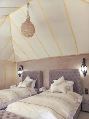 two beds in a room with a tent at The Luxury ERG Safari Camp in Merzouga