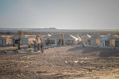 a group of houses in the desert with a dirt road at The Luxury ERG Safari Camp in Merzouga