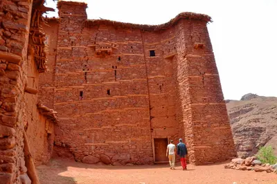 two men standing in front of a brick building at Dar Megdaz in Megdaz