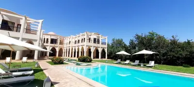 a large house with a swimming pool with chairs and umbrellas at villa blanche Marrakech in Marrakech